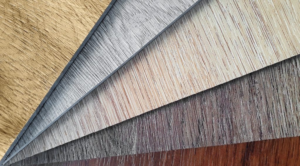 close up wooden vinyl spc flooring samples swatch showing variety of wooden texture. macro view sample stack of vinyl sheet catalog for interior floor covering.